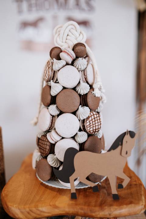 Foto em detalhe de torre de macarons em tons de marrom e branco.'