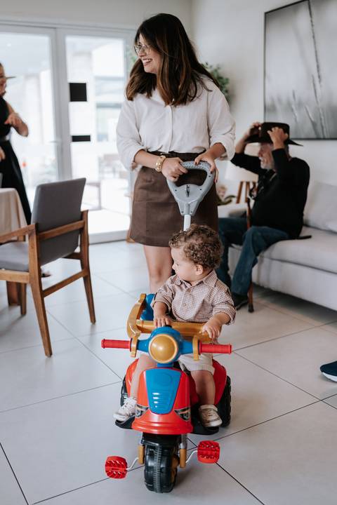 Foto do aniversariante brincando em um andador de avião colorido.'