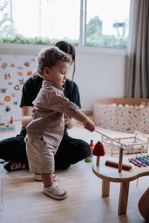 Foto do aniversariante brincando com peças de madeira.'
