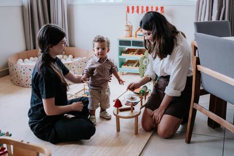 Foto do aniversariante interagindo com familiares na área de brinquedos.'