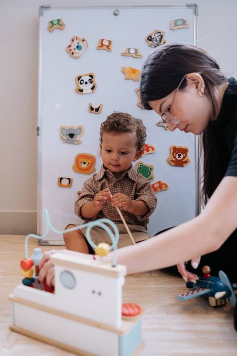 Foto do aniversariante brincando com aramado pedagógico sob supervisão.'