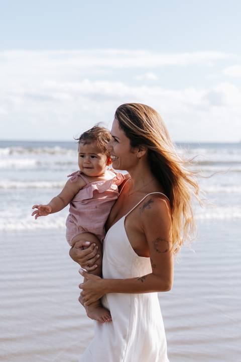 Foto aproximada da mãe abraçando a filha com o vento no cabelo.'