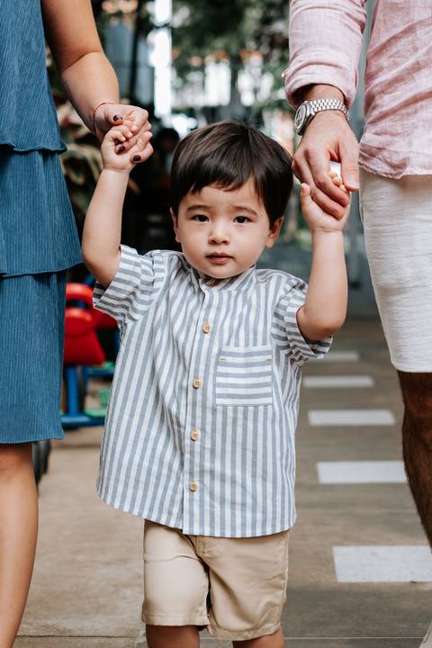 Foto do aniversariante sendo segurado pela mão chegando na festa.'
