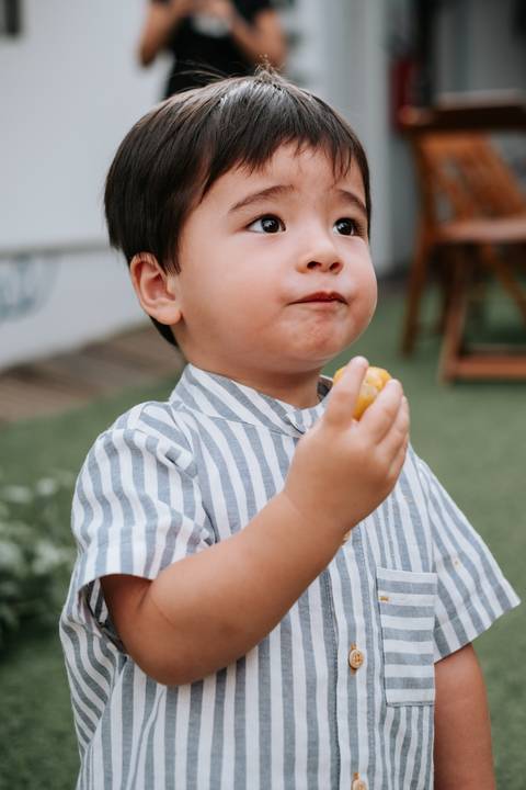 Foto espontânea do Arthur comendo um salgadinho da festa.'
