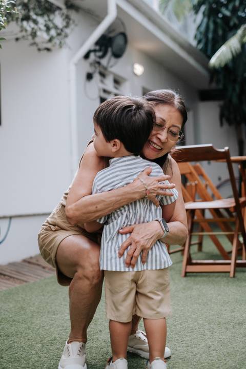 Foto do aniversariante recebendo um abraço carinhoso de uma convidada.'