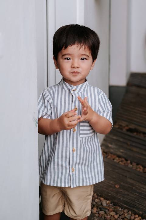 Foto de close do aniversariante usando uma camisa listrada clássica.'
