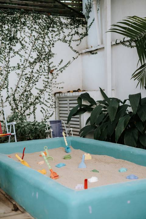 Foto de área de lazer com piscina de areia e brinquedos para as crianças.'