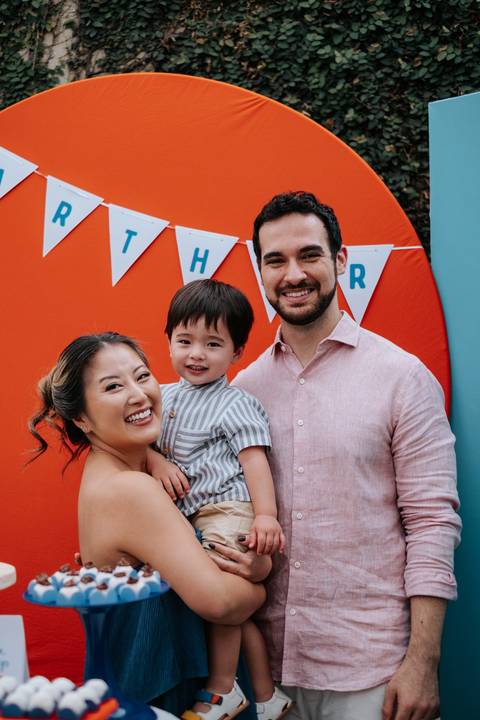 Foto oficial da família reunida em frente ao painel decorativo da festa.'