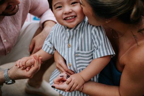 Foto aproximada dos pais brincando com o Arthur no chão.'