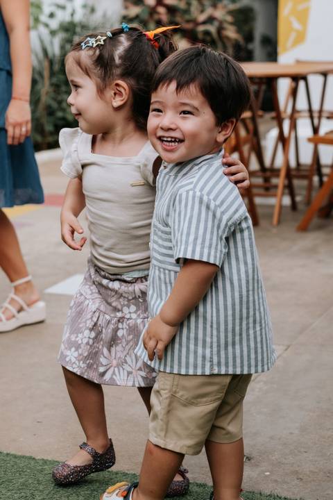 Foto em detalhe do Arthur brincando de mãos dadas com outra criança.'