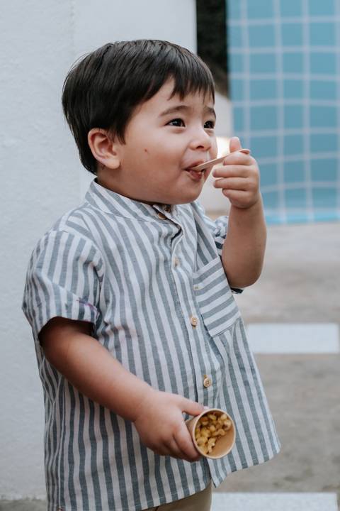 Foto do Arthur aproveitando o buffet infantil durante a comemoração.'