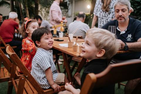 Foto do aniversariante interagindo com amiguinhos na mesa.'