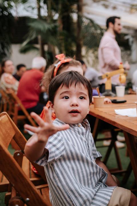 Foto espontânea do Arthur sorrindo e acenando durante a brincadeira.'