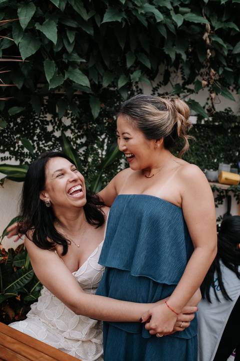 Foto da mãe do Arthur gargalhando com uma amiga na festa.'