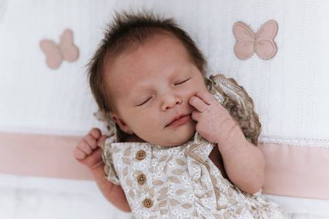 Foto da bebê Olívia dormindo calmamente em seu berço decorado.'