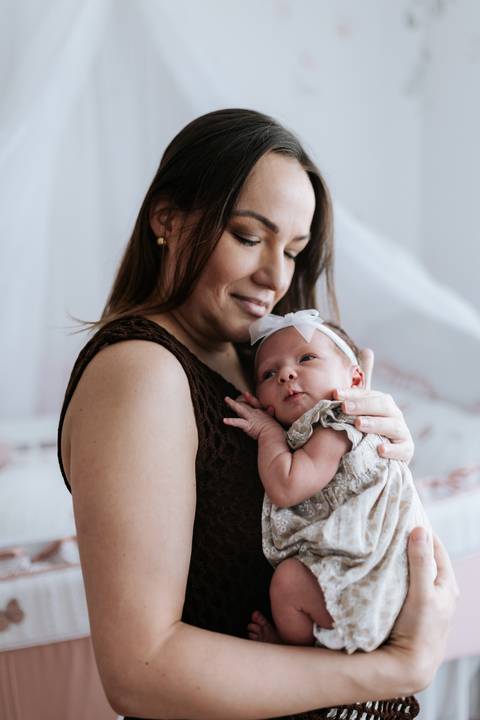 Foto da mãe segurando a Olívia no colo e olhando com ternura.'