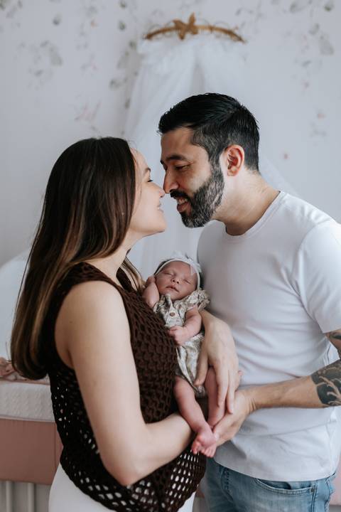 Foto de perfil do casal com os rostos próximos e a Olívia no colo.'