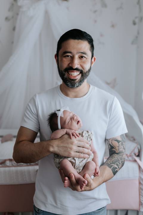 Foto do pai sorridente segurando a bebê Olívia no colo.'