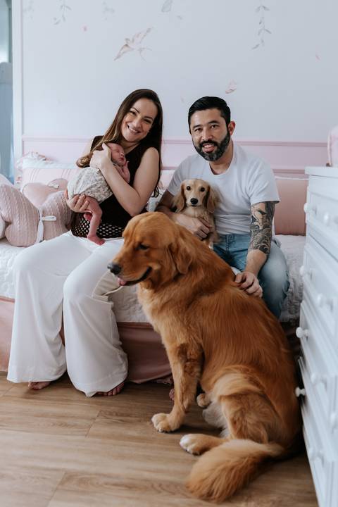 Foto da família reunida na cama com seus dois cachorros.'