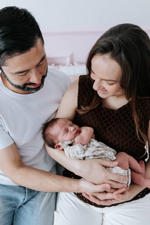 Foto do casal observando a Olívia dormindo em seus braços.'