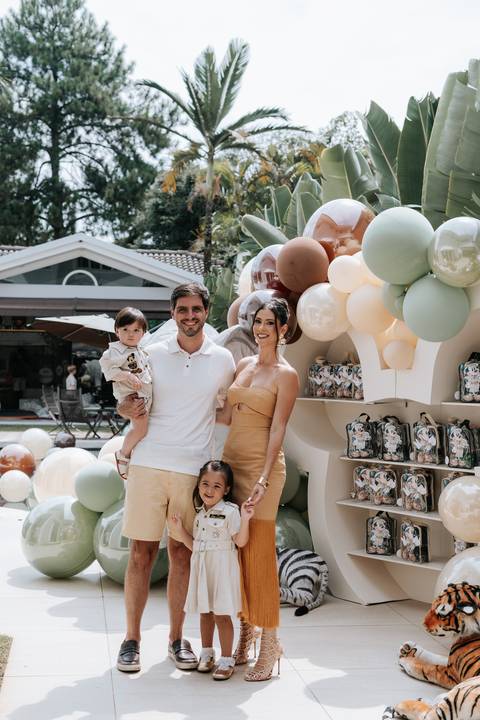Foto da família posando com a decoração de balões ao fundo.'