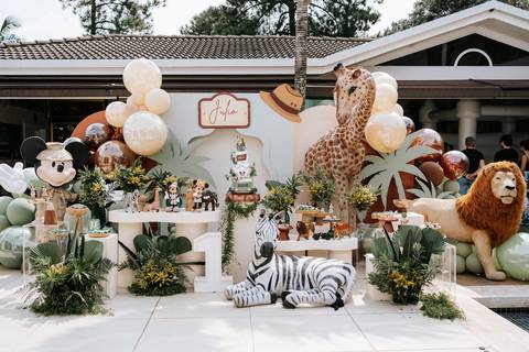 Foto panorâmica da mesa de doces com girafa e leão gigantes.'