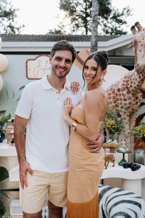 Foto romântica do casal sorrindo em frente à decoração rústica do Safari.'