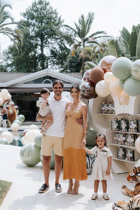 Foto oficial da família sorridente em frente à decoração temática.'