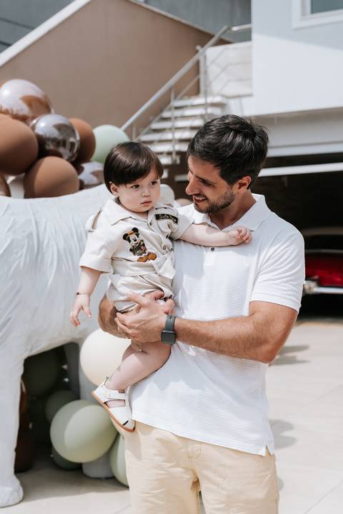 Foto do pai segurando o aniversariante no colo em momento de carinho.'