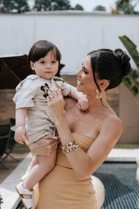 Foto da mãe com o aniversariante no colo sorrindo para a câmera.'