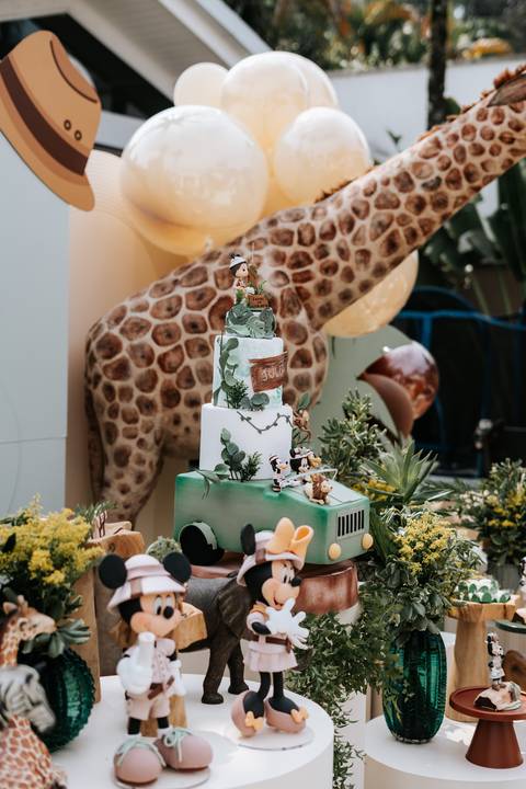 Foto do bolo temático posicionado em frente à escultura de girafa.'