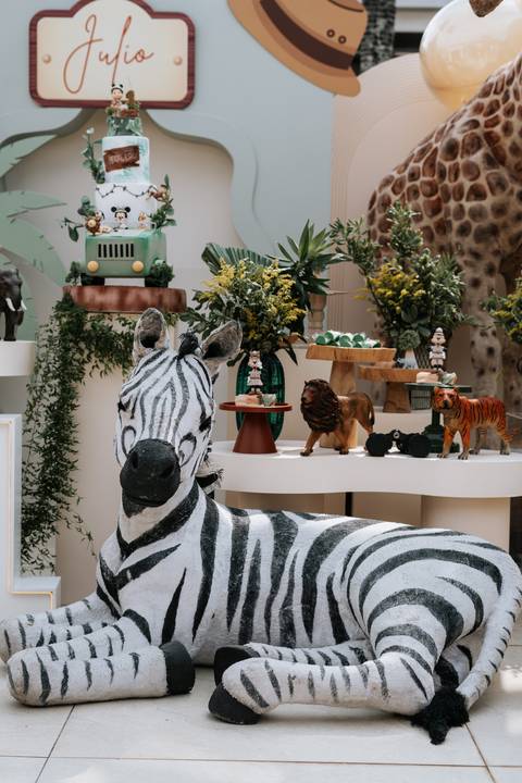 Foto em detalhe da decoração com zebra, leão e folhagens naturais.'