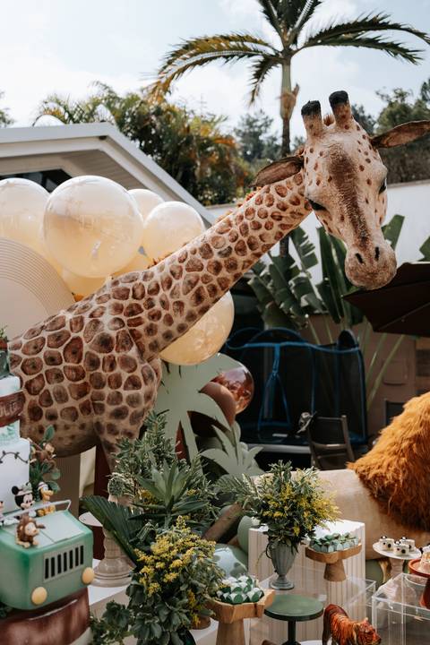 Foto da escultura de girafa gigante integrada ao cenário da festa.'