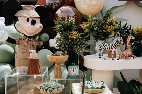 Foto panorâmica da mesa de doces com o Mickey de pelúcia e animais.'
