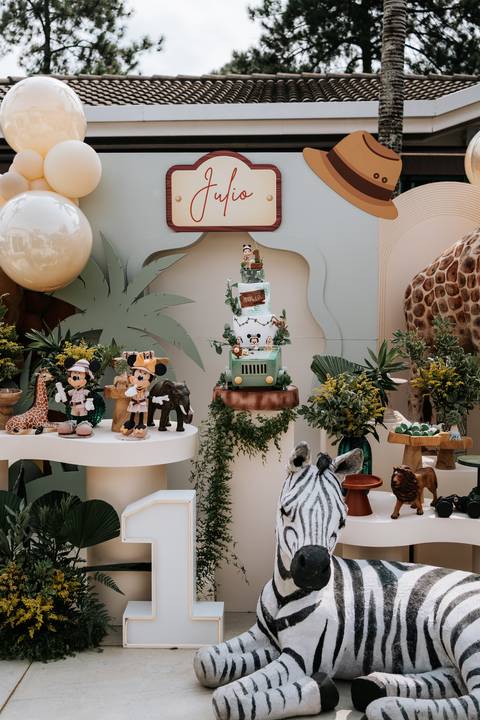 Foto em detalhe da mesa do bolo com o Mickey e a Minnie em trajes de explorador.'