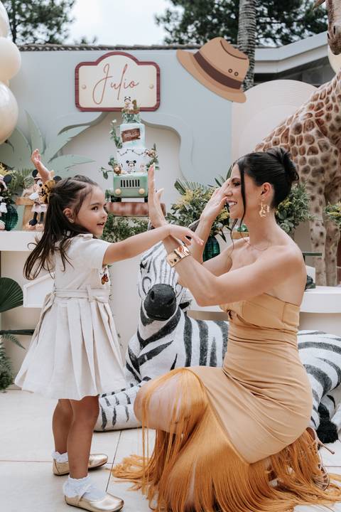 Foto da mãe brincando com a filha em frente à decoração.'
