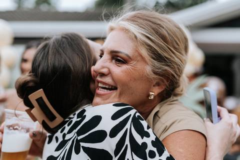 Foto de abraço emocionante entre duas convidadas durante o evento.'