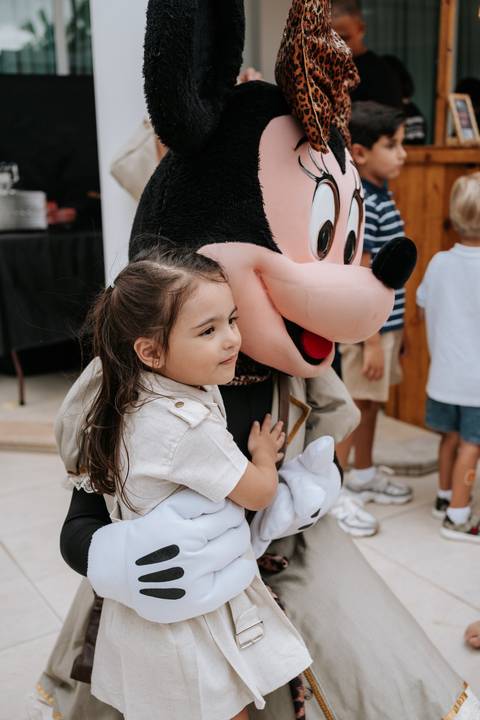 Foto carinhosa da irmã do aniversariante abraçando o boneco do Mickey.'