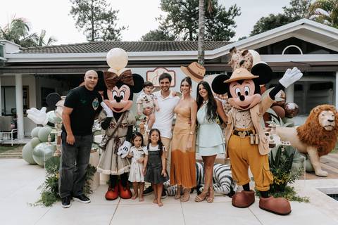 Foto da família e personagens em frente ao cenário de animais gigantes.'