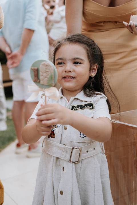 Foto aproximada da irmã do aniversariante segurando um pirulito de cristal.'