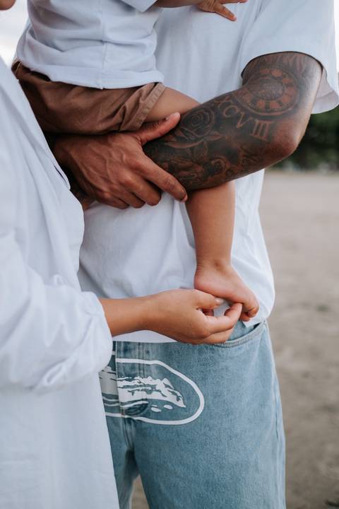 Foto aproximada do casal abraçado com o filho entre eles.'