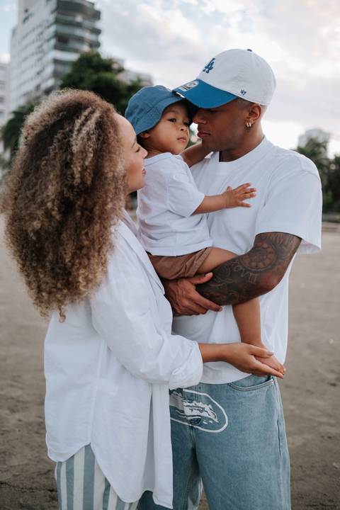 Foto de família abraçada beira-mar. '