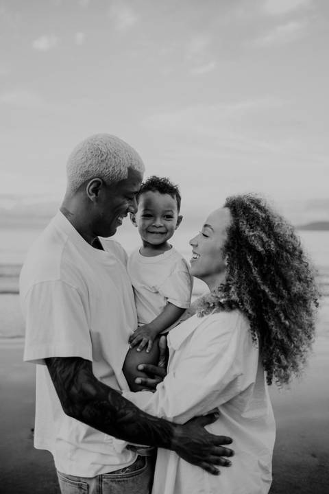 Foto em preto e branco da família sorrindo unida na praia.'