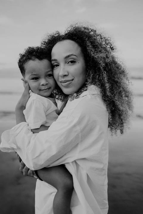 Foto em preto e branco da mãe e filho sorrindo abraçados.'