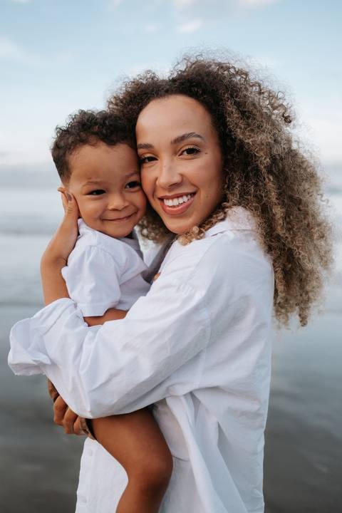 Foto de close da mãe com o rosto colado ao do filho, ambos sorrindo.'