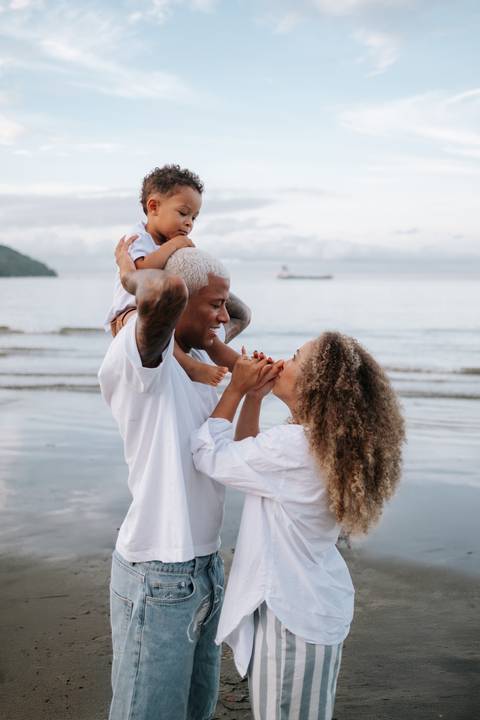 Foto da família completa brincando com o pequeno nos ombros do pai.'