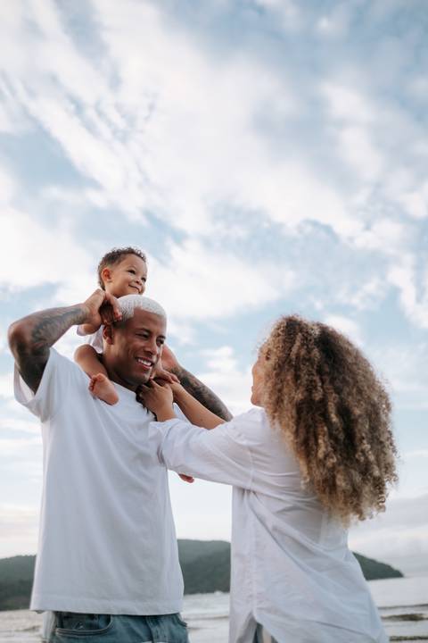 Foto aproximada da família sorrindo e interagindo na praia.'