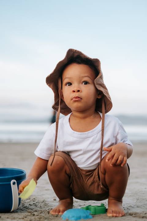 Foto de close do rosto do bebê usando um chapéu bucket de linho.'