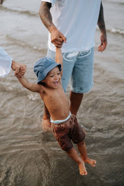 Foto espontânea do bebê com os braços abertos feliz na praia.'