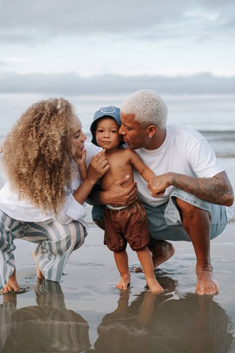 Foto da família agachada na areia. '